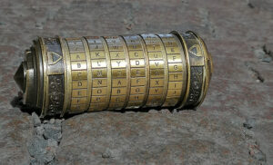 Närbild på en mässingsfärgad kryptex i metall som används i vårt utomhusspel the Da Vinci Quest. Kryptexen ligger på kullersten.